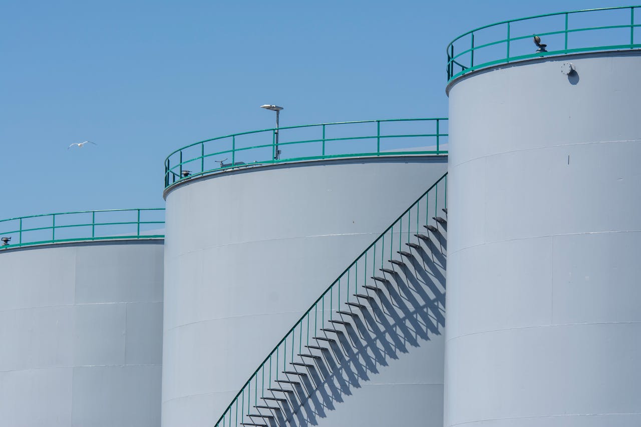 why-choose-us Industrial storage tanks with metal stairways under a clear blue sky, highlighting industrial architecture.